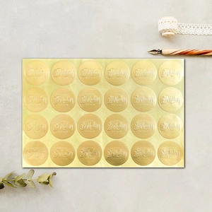 Detail view of 24 gold foil Happy Birthday stickers on grey textured background with props