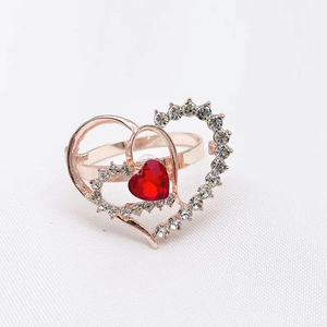 Macro shot of rose gold double heart ring with red gemstone and sparkling crystals