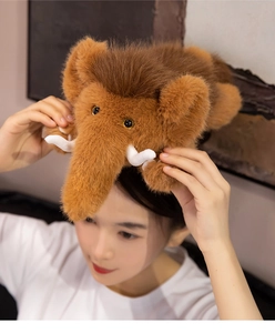 Close-up of a plush mammoth doll with soft brown fur, curved white tusks and gold eyes