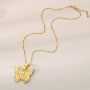 Detailed close-up of a golden butterfly pendant with sparkling zircon accents on an O-chain