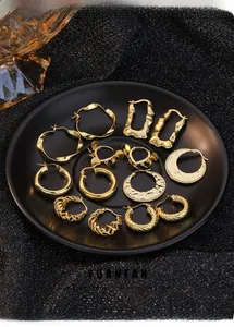 Collection of seven pairs of assorted gold plated earrings displayed on a black matte tray