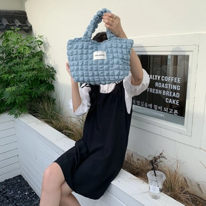 Detail shot of a light blue bubble textured canvas tote bag with a woven label accent