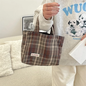 Macro shot of retro plaid tote bag fabric with brand label and durable woven handles