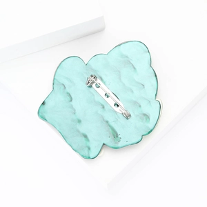 Detail view of the secure silver metal safety pin clasp on turquoise resin brooch back
