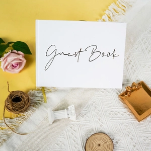 Libro de visitas de boda blanco elegante con caligrafía negra en un entorno romántico