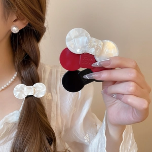 Close-up of resin flower hair clips in cream white, burgundy and black with wer logo