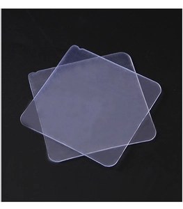 Detailed close-up of two transparent square adhesive pads with rounded edges on black surface