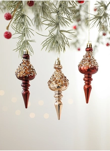 Close-up of champagne and burgundy finial drop Christmas ornaments with glitter details