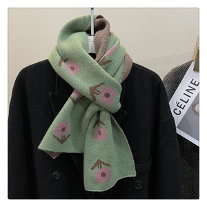 Detail of green knitted scarf with pink floral patterns on a black coat