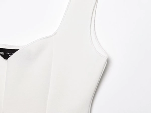 Vista dettagliata del tessuto a maglia bianco e delle etichette delle taglie sul top senza maniche