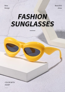 Close-up of bright yellow chunky frame cat-eye sunglasses with dark grey lenses