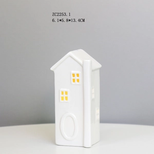 Macro shot of minimalist white ceramic house night light showing small yellow windows and texture
