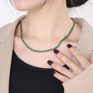 Close-up of gold plated titanium necklace featuring square green zircon gemstones worn by model