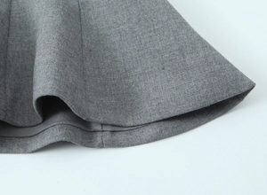 Vue détaillée montrant la texture fine et l'ourlet du tissu de la jupe gris foncé