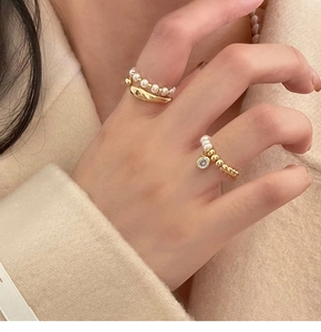 Détail de bagues plaquées or avec perles et zircon porté par un mannequin sur les doigts