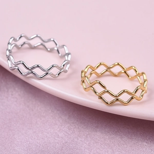 Close-up of gold and silver wave rings with polished finish on a ceramic plate