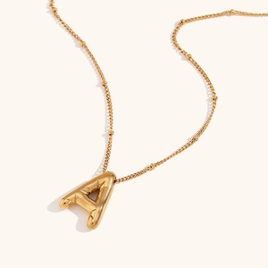 Macro view of gold stainless steel necklace featuring a 3D letter A pendant on a bead chain