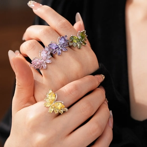 Gros plan d'une bague papillon avec des pierres précieuses colorées sur la main d'un mannequin