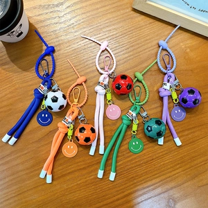 Colorful football braided rope keychains with smile charms on natural wood surface