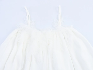 Close-up of intricate lace trim and floral texture on a white chiffon camisole dress