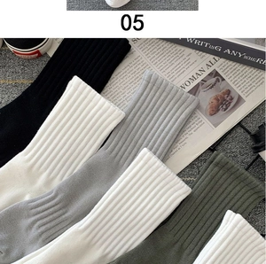 Close-up of four-color cotton crew socks in black white grey and green with ribbed texture