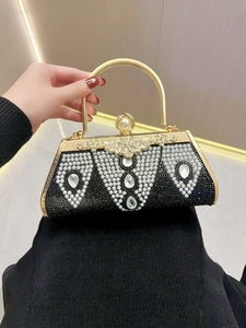 Close-up of black evening clutch with pearls, crystals and gold metal handle