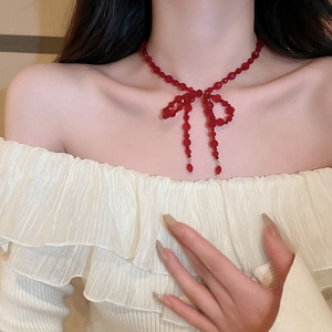 Détail du collier à nœud en cristal rouge sur le cou montrant un style de bijoux perlé