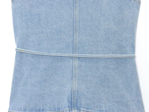 Détail de la texture denim bleu clair et du design à bride horizontale sur le gilet