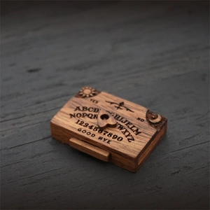Scatola a cassetti Ouija in legno marrone scuro con cursore a cuore su sfondo ligneo