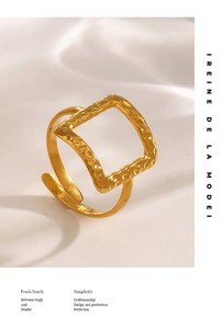Macro shot of gold hammered texture on square hollow ring over white fabric