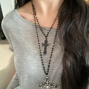 Close-up of gothic double-layered necklace with black bead chain and rhinestone cross pendants