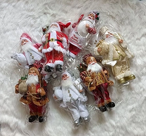 Multiple Santa Claus ornaments in various outfits on a white plush background
