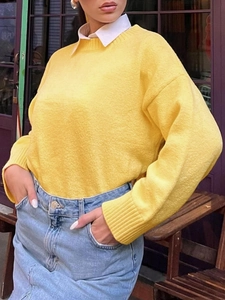 Detail eines gelben Strickpullovers mit Rundhalsausschnitt und weißem Hemdkragen