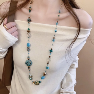 Detail of colorful long beaded necklace with boho style layering on a model