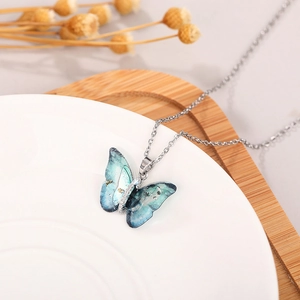 Close-up of a gradient blue-green butterfly pendant necklace with silver chain and zircons