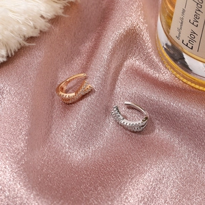 Close-up of rose gold and silver X-shaped ear cuffs with micro-set zircon stones