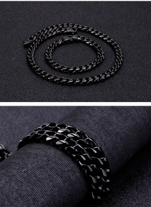 Detail of black Cuban link necklace and bracelet set with ornate engraved metal clasp