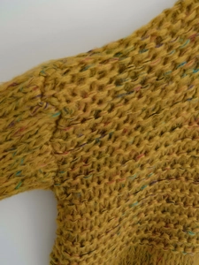 Detailed macro view of ginger yellow chunky knit sweater with colorful nep yarn texture