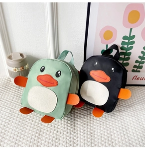 Detail of cute penguin shaped nylon backpack for toddlers in green and black colors