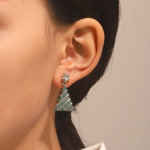 Close-up of model wearing sparkling green Christmas tree earrings with star stud detail