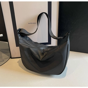 Detail of a large black waterproof nylon dumpling bag on a light beige display surface