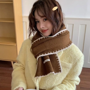 Winter knit brown scarf with white zigzag edge trim and brand label shown on a model