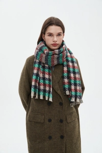 Detail of red and green plaid scarf with soft tassels over a dark green wool coat