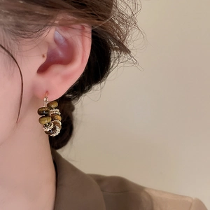 Detail of vintage gold pearl and brown tiger eye stone earrings worn by a model
