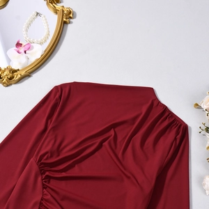 Close-up of side ruched details on elegant deep red long sleeve dress with pearl decor