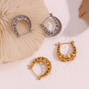 Detail of 18K gold and silver hollow heart U-shaped hoop earrings on watery stone surface