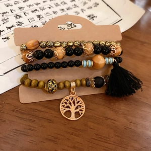 Detail of bohemian layered sandalwood bracelets with life tree pendant and black tassel