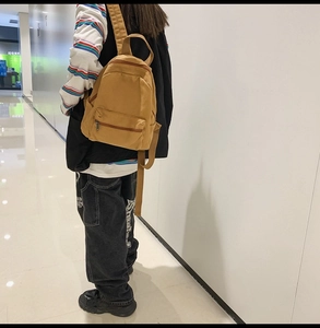 Seitenansicht des khakifarbenen Canvas-Rucksacks mit Mehrschicht-Reißverschlüssen und Seitentasche