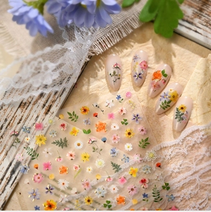 Detailed shot of Monet floral nail stickers applied on almond-shaped pink manicures