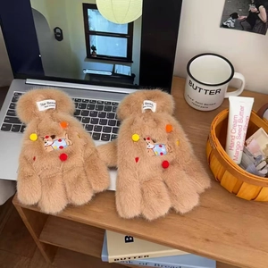 Detail of plush brown dachshund gloves with 3D pom-poms and warm faux fur texture